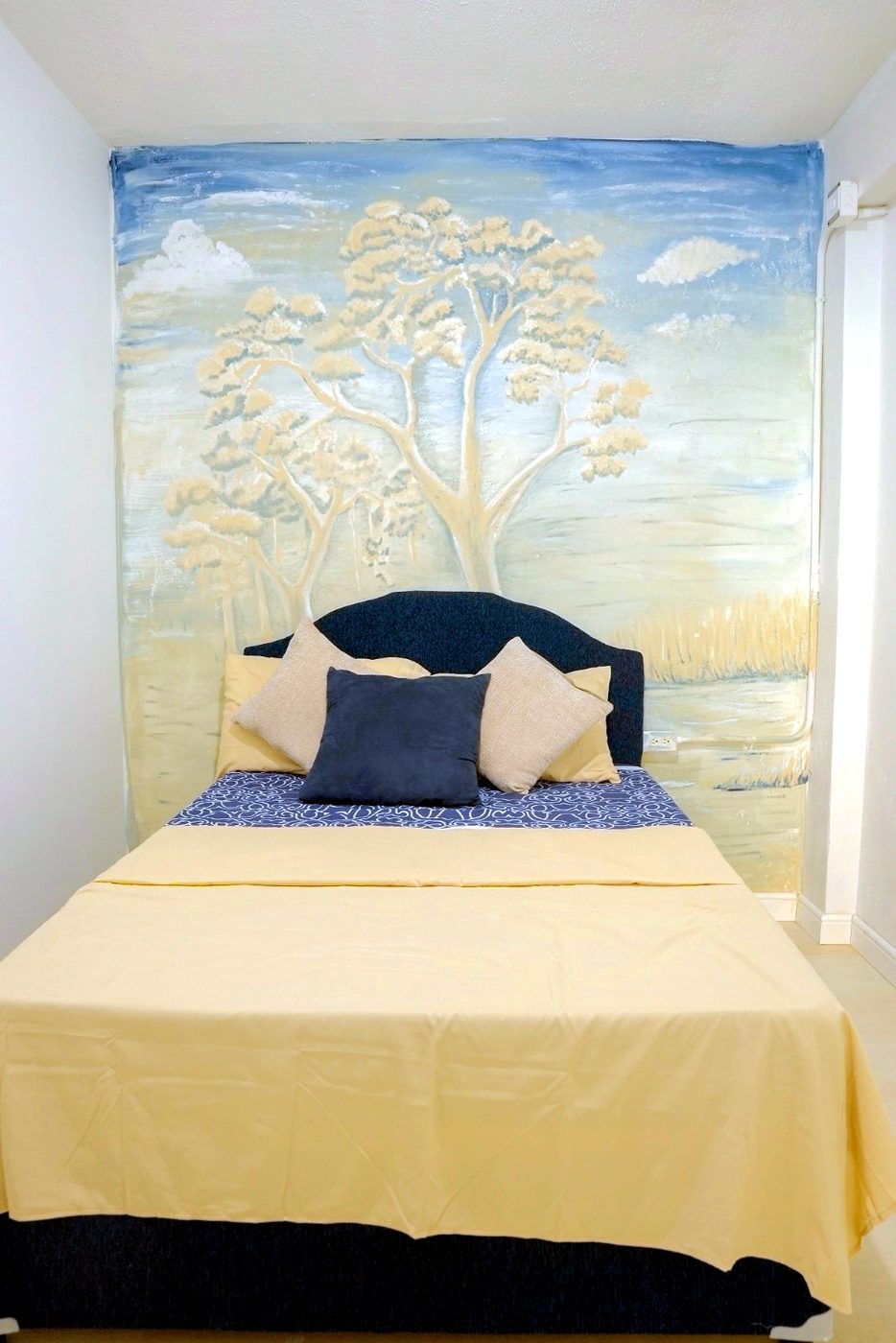 A resident room with a hand-painted landscape mural above the bed