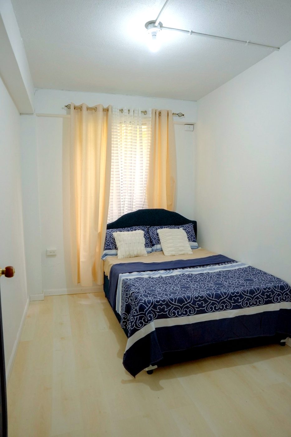 A private room with a double bed and soft cream curtains